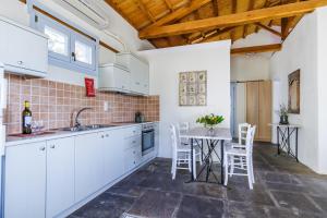 a kitchen with white cabinets and a table with chairs at Althea in Panormos Skopelos