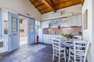 Una cocina con gabinetes blancos y una mesa y sillas. en ALTHEA, en Panormos Skopelos 20 fotos más