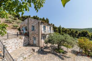 una vista exterior de una casa de piedra con un árbol en ALTHEA, en Panormos Skopelos