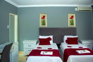 een slaapkamer met 2 bedden met rode en witte lakens bij Muofhe Graceland Lodge in Thohoyandou
