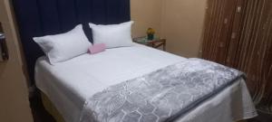 ein Schlafzimmer mit einem weißen Bett mit einer rosa Karte in der Unterkunft Karee Gardens B&B in Springs