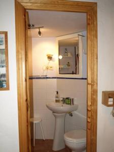 een badkamer met een wastafel, een toilet en een spiegel bij La Casa Chica de Luis in Fuenteheridos