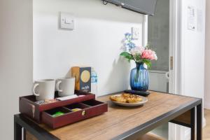 a table with a plate of food and a vase of flowers at Holloway Budget Apartment - 1 Minute to Emirates Stadium - Next to Station - City Center in London
