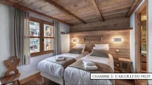 Chalet K120 - Village du Praz - Courchevel في كورشوفيل: سريرين في غرفة بجدران خشبية