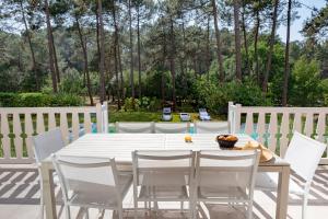 einen weißen Tisch und Stühle auf einer Terrasse in der Unterkunft villa familiale dans cadre exceptionnel, piscine chauffée-AG19 in Lacanau