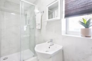 uma casa de banho branca com um lavatório e um chuveiro em Holloway Budget Apartment - 1 Minute to Emirates Stadium - Next to Station - City Center em Londres