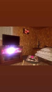 1 dormitorio con TV, cama y mesa en Seosko domacinstvo Becirovic - Kukulik lodgings en Bijelo Polje