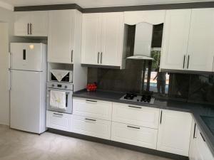 una cucina con armadietti bianchi e frigorifero bianco di Villa’s Tomris a Ortaca