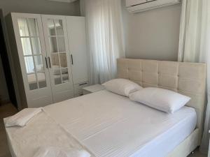 un letto bianco con due cuscini in una camera da letto di Villa’s Tomris a Ortaca