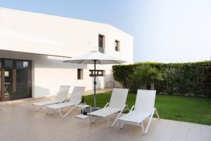 a group of chairs and an umbrella on a patio at Ville Edilia Vacanze in Marina di Ragusa