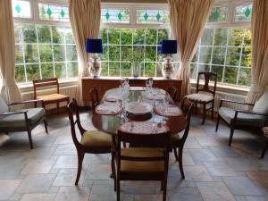 uma sala de jantar com mesa, cadeiras e janelas em Tullynacrunat Lodge em Castleblayney