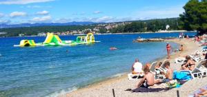 a group of people on a beach with water slides at UNIQUE Apartments Malinska in Malinska