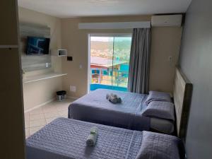 a bedroom with two beds and a window with a view at Pousada Mirante da Prainha in Arraial do Cabo