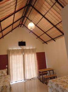 Zimmer mit einem Fenster, einem Tisch und einem TV in der Unterkunft Chalés Pôr Do Sol in Caparaó Velho