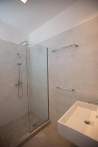 W łazience znajduje się szklana kabina prysznicowa i umywalka. w obiekcie TIKI BEACH STUDIOS w mieście Nea Makri