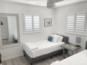 Habitación blanca con cama y espejo en Modern Apartment - 4 of 4 en Punta Gorda