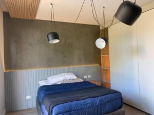 ein Schlafzimmer mit einem Bett mit blauer Bettwäsche und zwei Lichtern in der Unterkunft Mid-Century Veek - puro diseño in Belén de Escobar