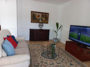 a living room with a couch and a flat screen tv at Vila Glória Guesthouse in Lagos