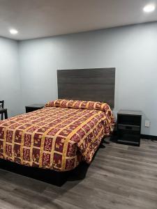 een slaapkamer met een bed met een deken erop bij Travel Inn Gilroy in Gilroy