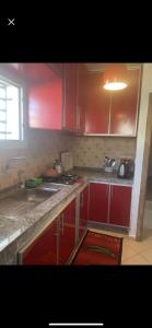 una cocina con armarios rojos y fregadero en شقة مفرشة, 