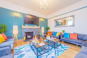 a living room with blue couches and a fireplace at Snowdon House, 8 bedrooms, sleep 16, close to Blackrock Sand in Porthmadog