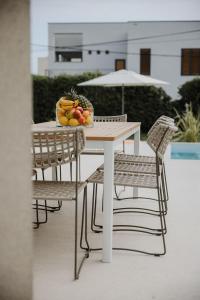un tavolo bianco con sedie e un cesto di frutta. di Villa Botanica - New family house near the sea a Kaštela (Castelli)