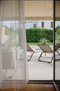 una vista su un patio con due sedie a sdraio attraverso una finestra di Villa Botanica - New family house near the sea a Kaštela (Castelli)