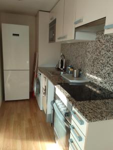 cocina con encimeras de granito y nevera blanca en Espectacular apartamento de alquiler en Santa Coloma Barcelona en Santa Coloma de Gramanet