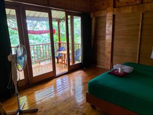 a bedroom with a bed and a balcony with sliding glass doors at Santi Garden Bungalows in Iboih