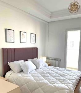 a white bedroom with a large bed with white pillows at Spacieux, chaleureux et élégant in Nabeul