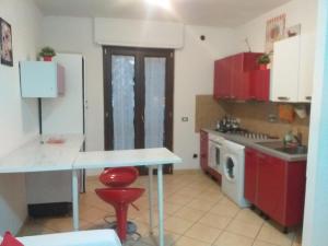 een keuken met rode kasten, een tafel en een wasmachine bij Hillary E Vale Room in Rome