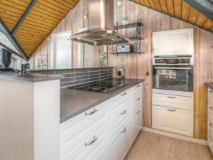 a kitchen with white cabinets and wood walls at Holiday home Væggerløse XXIII in Marielyst