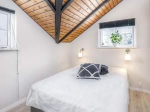 a bedroom with a white bed with a wooden ceiling at Holiday home Væggerløse XXIII in Marielyst