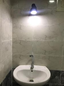 - un lavabo blanc dans la salle de bains pourvue d'une lumière sur le mur dans l'établissement Adam Pyramids, au Caire