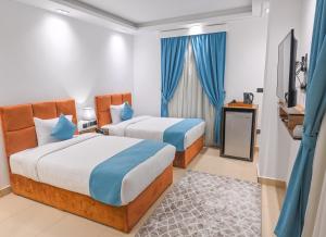 duas camas num quarto de hotel com cortinas azuis em Pyramids Gem Plaza Hotel & Apartments no Cairo