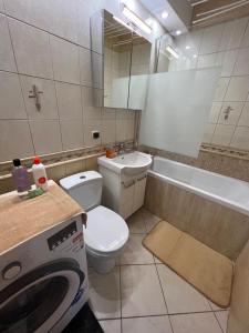 a bathroom with a toilet and a sink and a washing machine at Apartament Na Piątkę in Sopot