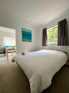 um quarto com uma grande cama branca e uma janela em Garden-nestled granny flat between winery and town em Armidale