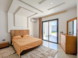 a bedroom with a bed and a large window at Villa AZMIR Djerba in Arkou