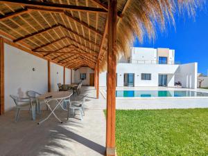 a patio with a table and chairs and a pool at Villa AZMIR Djerba in Arkou