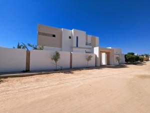 a white building in the middle of a dirt road at Villa AZMIR Djerba in Arkou