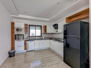 a kitchen with white cabinets and a black refrigerator at Villa AZMIR Djerba in Arkou