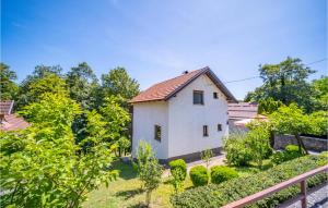a small white house in a garden with trees at Amazing Home In Duga Resa With House A Panoramic View in Duga Resa