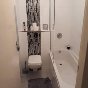 a bathroom with a toilet and a tub and a sink at 36 HydePark Apartments in Cape Town
