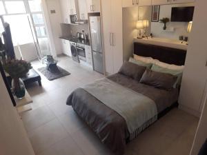 a bedroom with a large bed and a kitchen at 36 HydePark Apartments in Cape Town