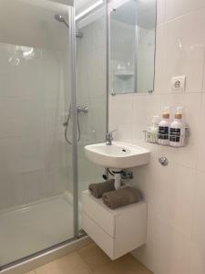 a white bathroom with a sink and a shower at Apartamento Flori, con terraza y a 300 m de la playa en Suances in Suances
