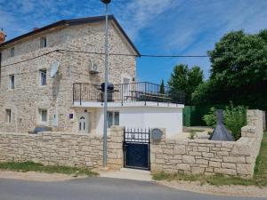 un antiguo edificio de piedra con puerta y balcón en Istrian APP House MARGARITA en Vilanija