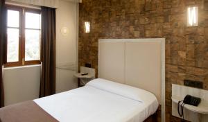 a bedroom with a white bed and a stone wall at Hotel La Rad in Galindo y Perahuy