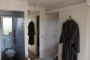 a bathroom with a toilet and a robe hanging on a door at Sha-Shaaa Luxury Mobile Home - Terra Park SpiritoS in Kolan