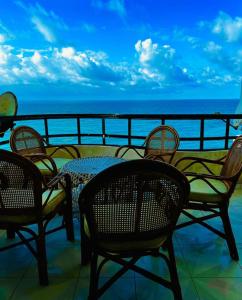 einen Tisch und Stühle auf einem Balkon mit Meerblick in der Unterkunft برج العزيزية بانوراما بحر للعائلات فقط in Alexandria