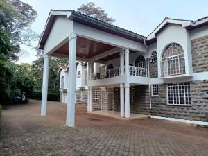 ナイロビにあるKaren white villaのレンガ造りの庭にバルコニーが付いた広い白い家